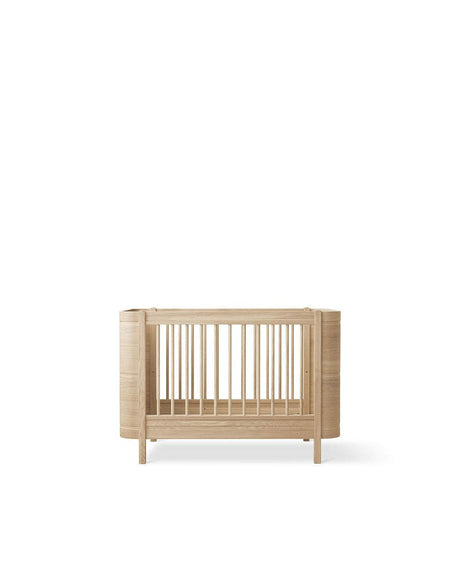 Wood Mini+ Babybett aus weiß geölter massiver Eiche mit höhenverstellbarem Lattenrost und abnehmbaren Gitterstäben, skandinavisches Design für Babys bis 3 Jahre.